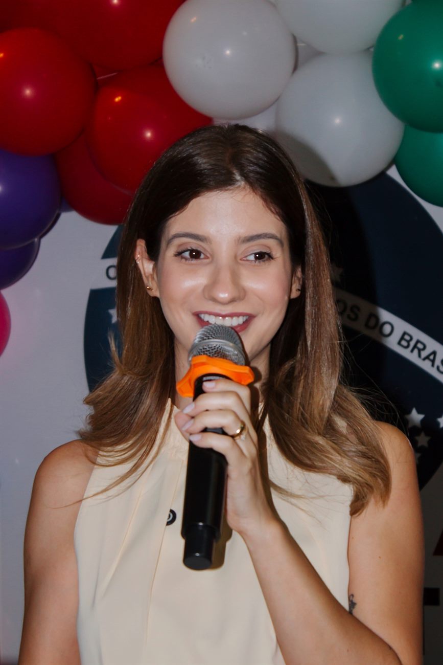 Mariana Lobo sorrindo ao microfone durante palestra